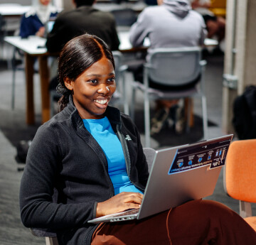 A student smiling at a laptop