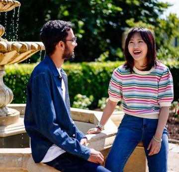 Two students outside sat by a fountain