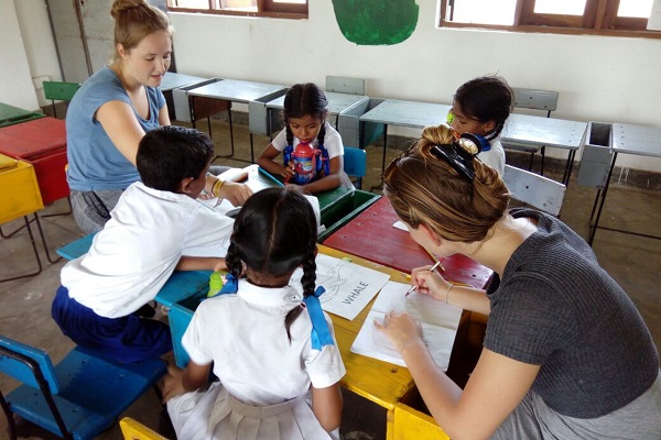 Volunteer sitting around a table with school children