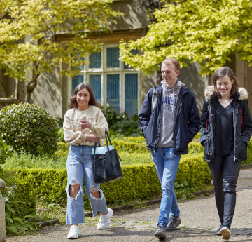 Three students walking outside the Abbey on Singleton Campus 