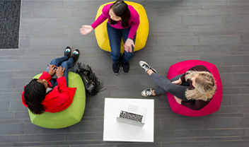 A bird's eye view of three students having a discussion n comfy chairs