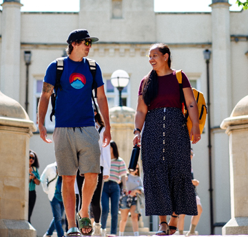 Two students outside walking towards the camera
