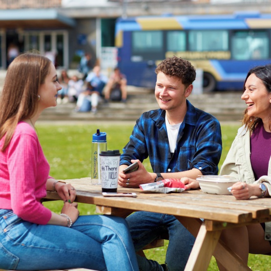 Three students sitting on a bench outside Fulton House