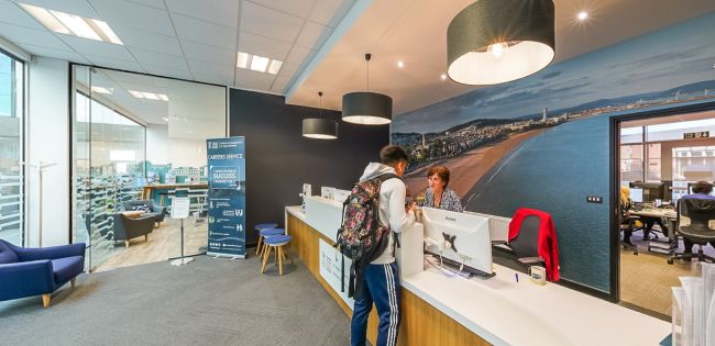 Reception area where a student speaks to staff at a modern service desk