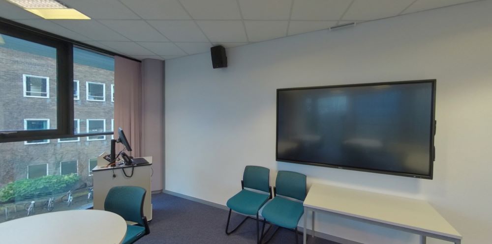 Modern teaching room with screen, chairs, lectern, and window view of building