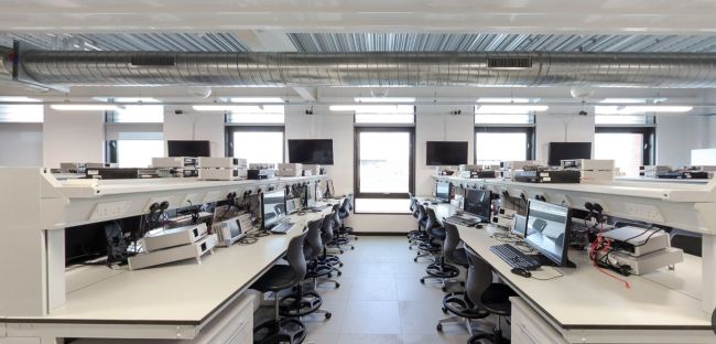 Electrical lab with rows of desks, computers, testing equipment and stools