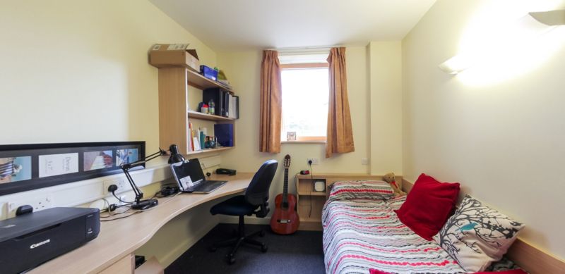 Student bedroom with single bed, study desk, shelving and window