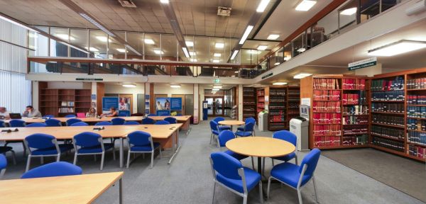 Library study hall with desks, blue chairs and bookshelves