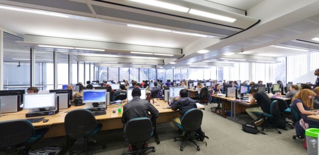 PC room with rows of computers and students working at desks