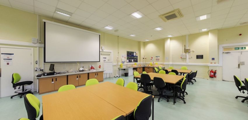 Paramedic sciences teaching room with group tables and projector screen