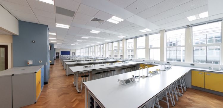 Science teaching lab with workbenches, stools, sinks, and large windows