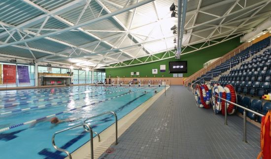 Large indoor swimming pool with lane dividers and swimmers in the water